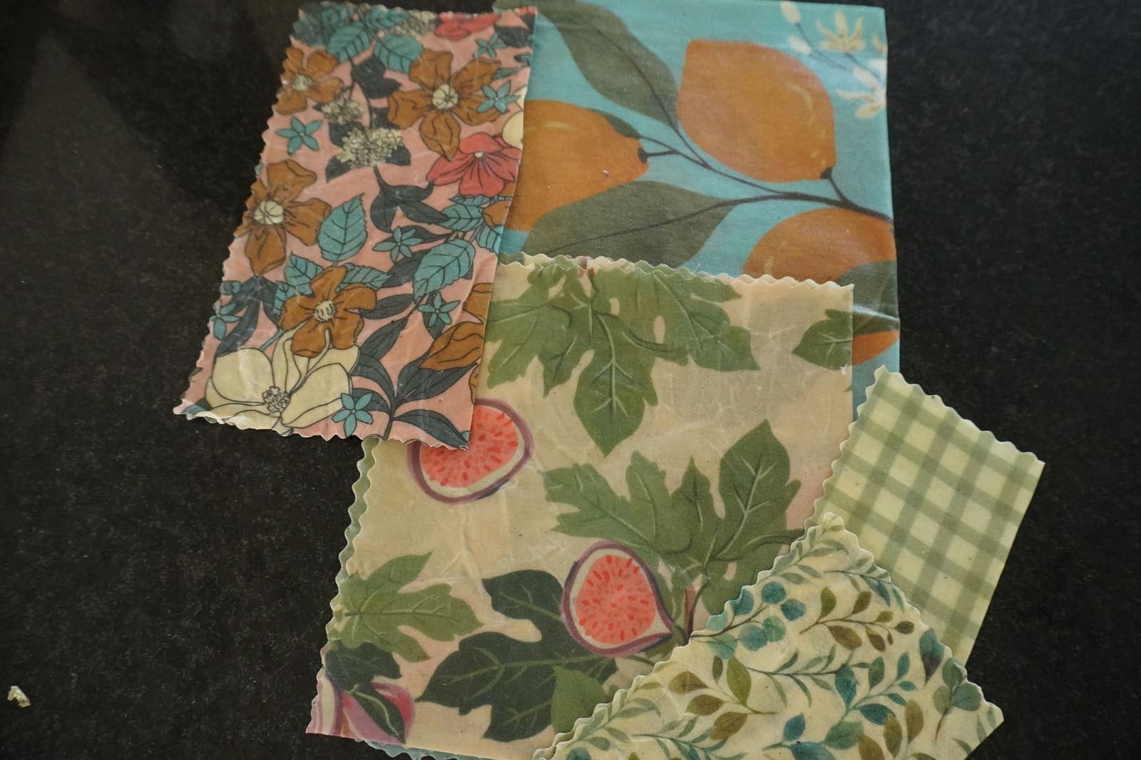 Cuatro wraps de cera de abeja con distintos patrones florales dispuestos sobre granito oscuro