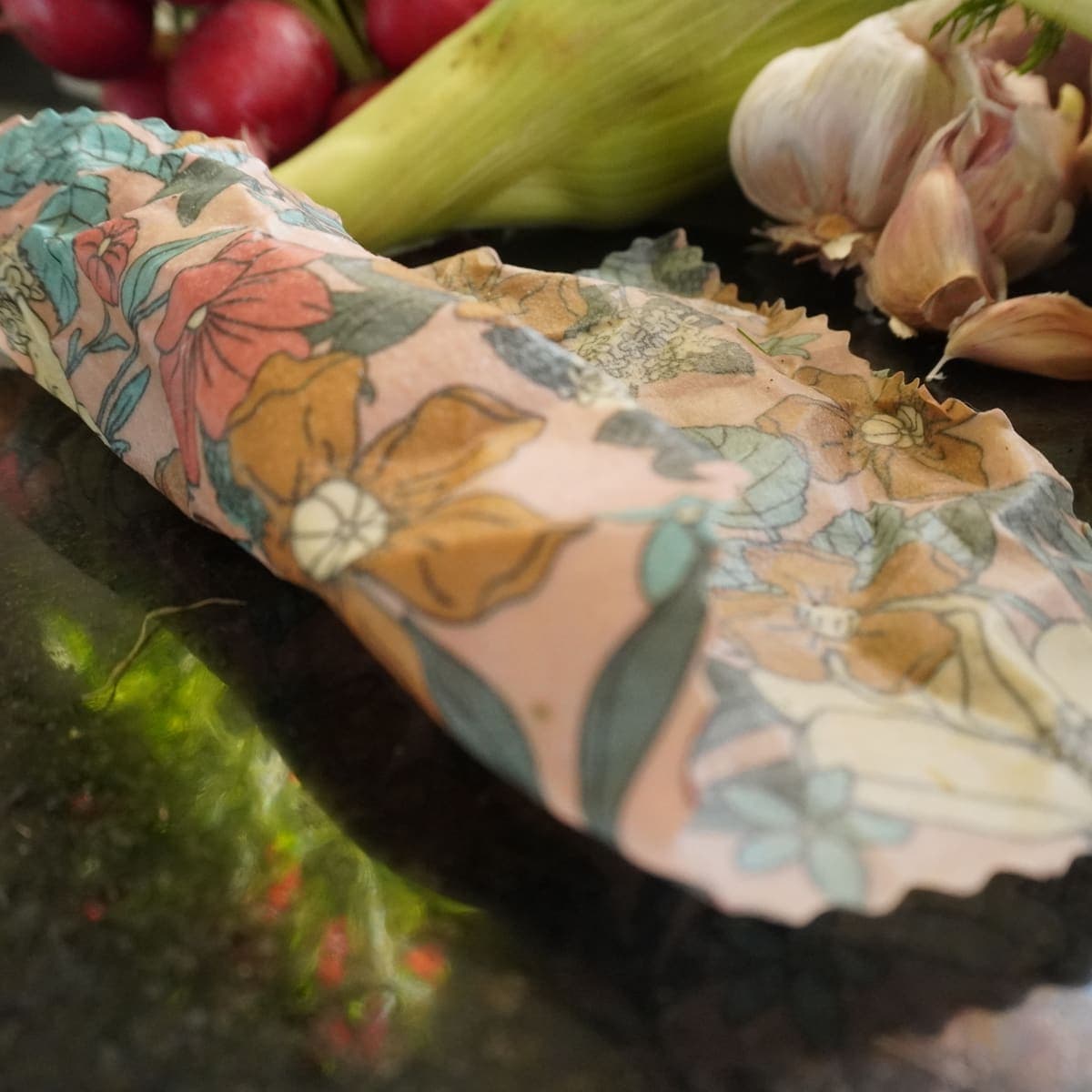 Wrap floral extendido sobre granito con ingredientes de cocina alrededor